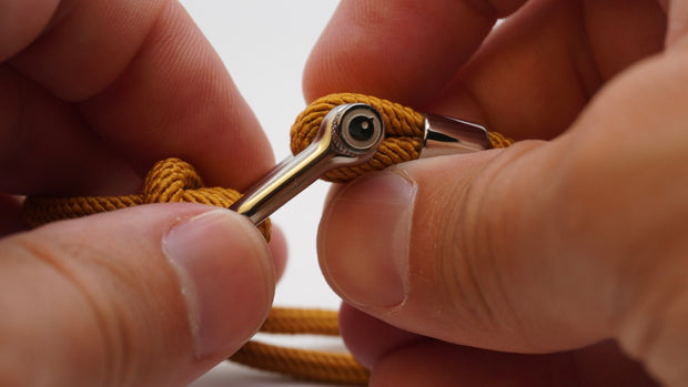 Close-up of hands holding a nautical shackle rope bracelet